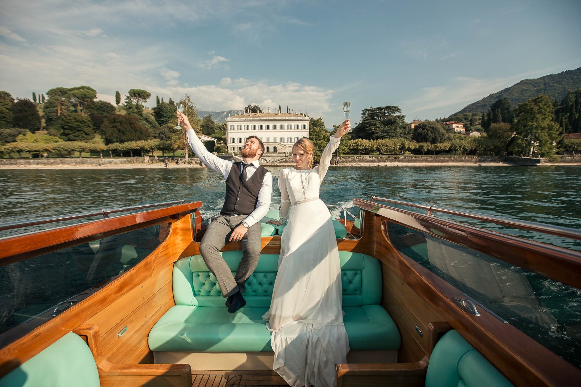 Lake Como wedding photographer: bride and groom on boat at lake Como for their wedding photos with Villa Melzi as background